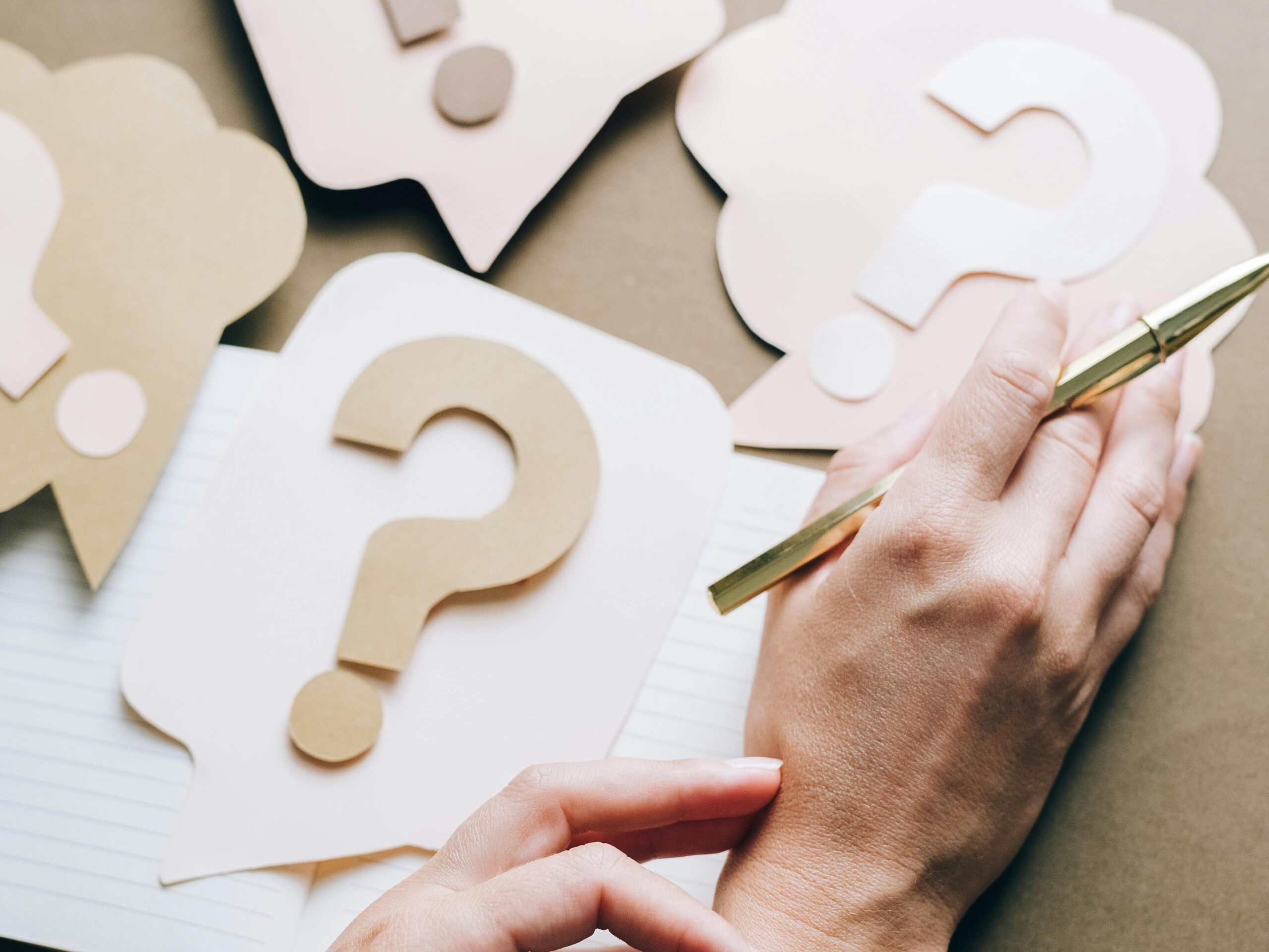 pexels-photo-5428825-5428825 Photo of paper question marks with hands and a pen suggesting curiosity and inquiry.